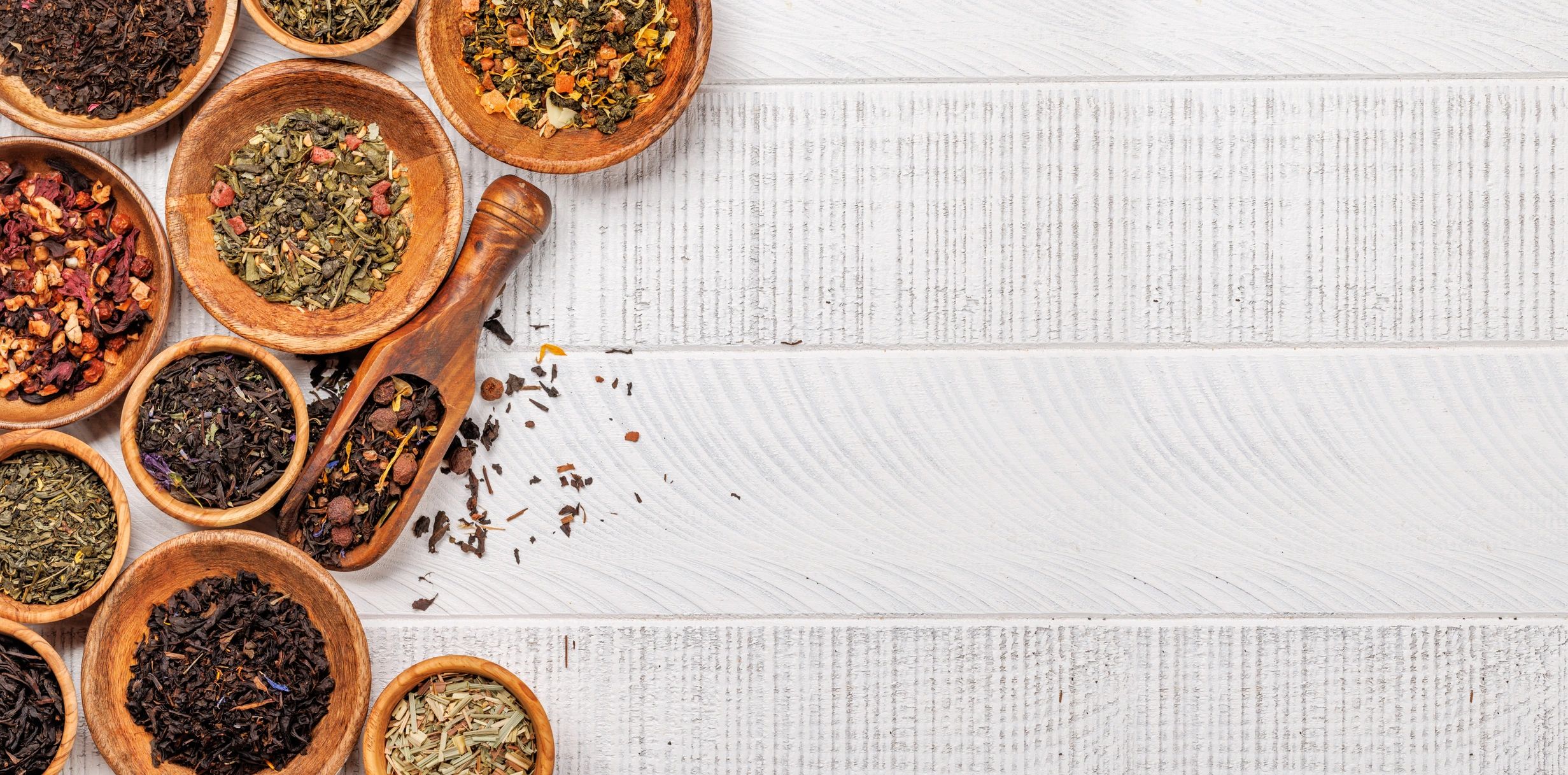 Assorted herbal teas in wooden bowls arranged flat lay