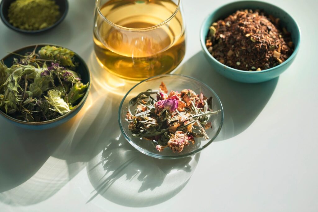 Herbal tea, tea cup with various dried tea leaves and flowers shot from above on white table